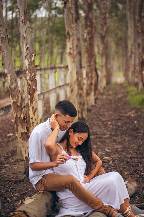 Free A couple joyfully sits together in a serene forest setting, sharing a tender moment. Stock Photo