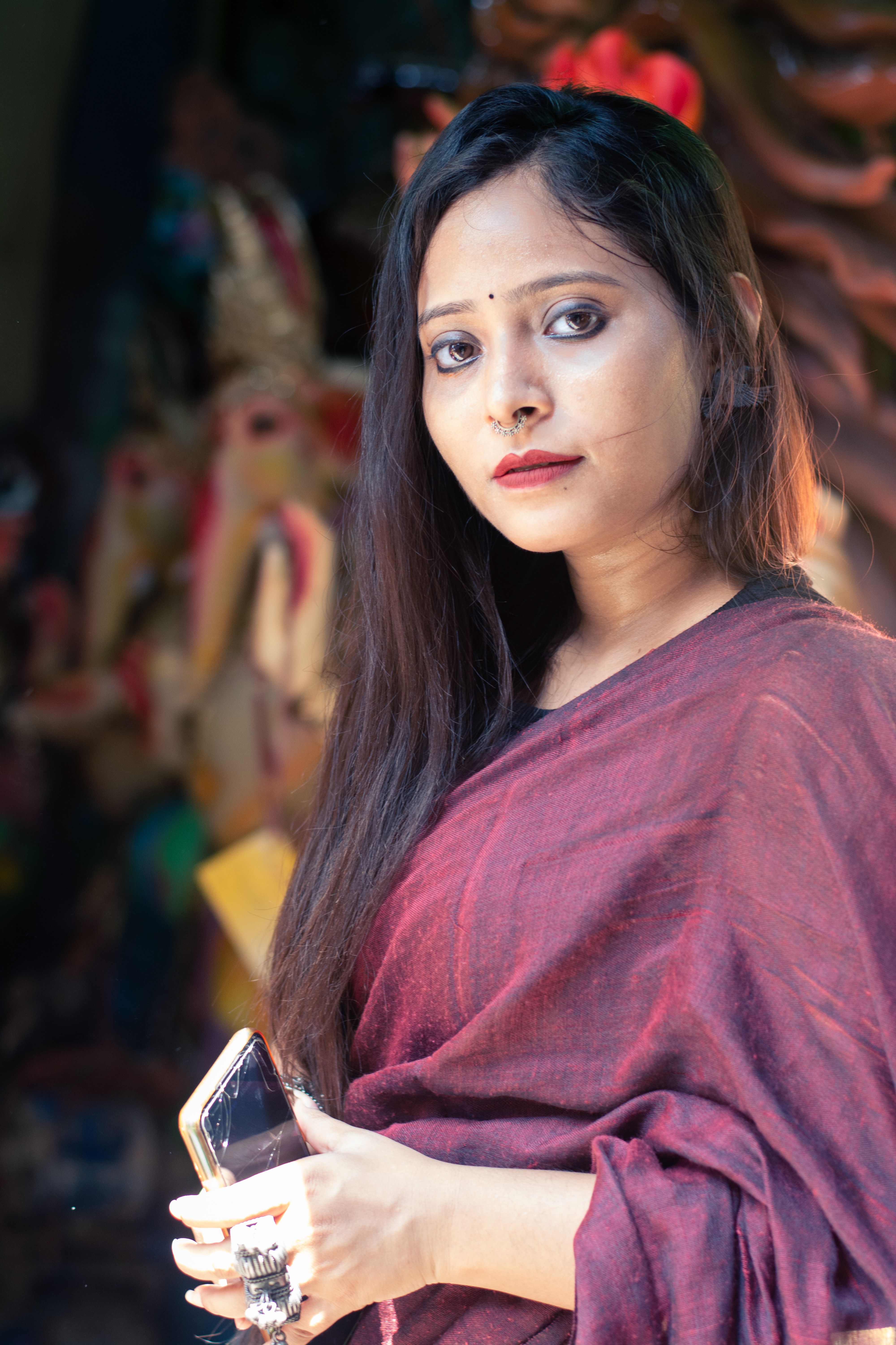 Elegant portrait of a young woman in Kolkata holding a smartphone.