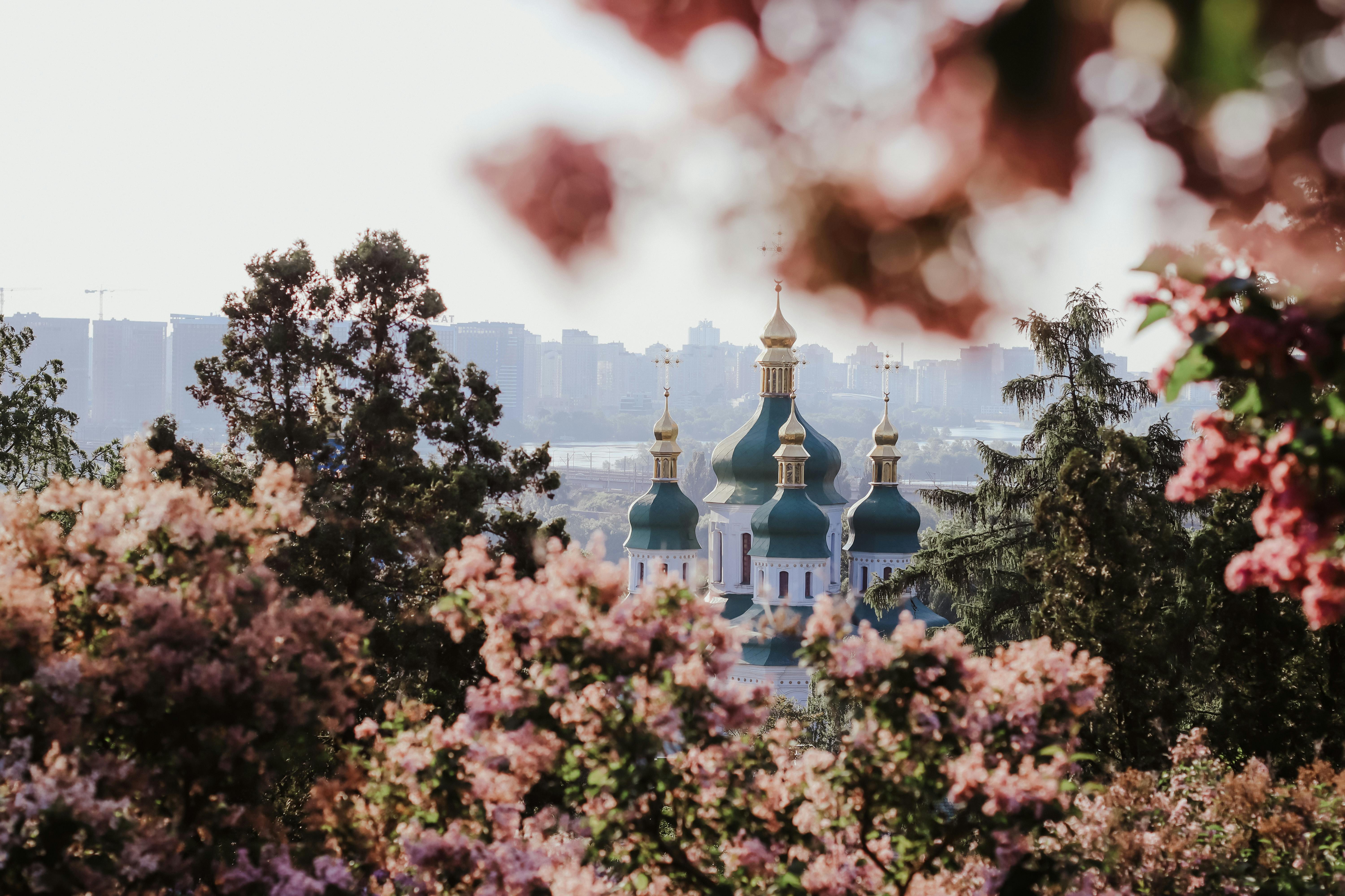 Beautiful view of Kyiv's St. Andrew's Church framed by vibrant spring blossoms.