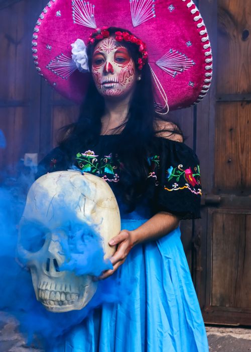 Free Colorful portrait of woman in traditional Day of the Dead costume with face paint and large skull. Stock Photo
