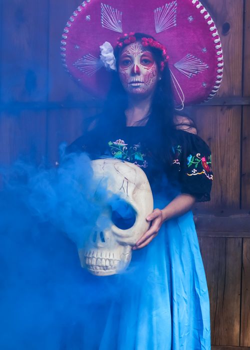 Free A woman in Dia de Muertos attire holds a skull amid colorful smoke. Traditional and vibrant. Stock Photo