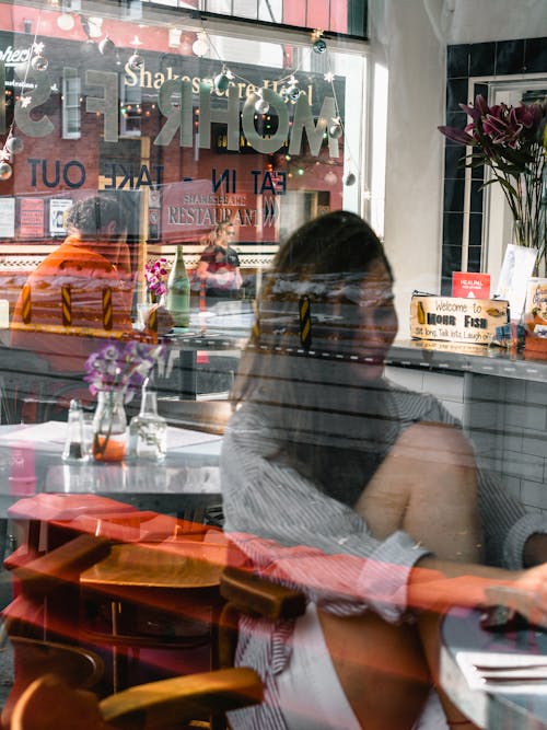 無料 ガラスパネルボードの横に座っている女性 写真素材