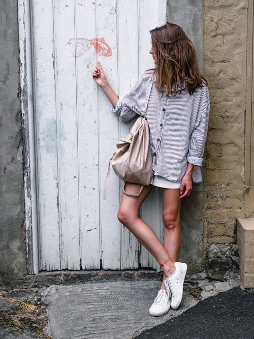Woman Wearing Gray Long-sleeved Shirt Looking Side While Leaning on Wall
