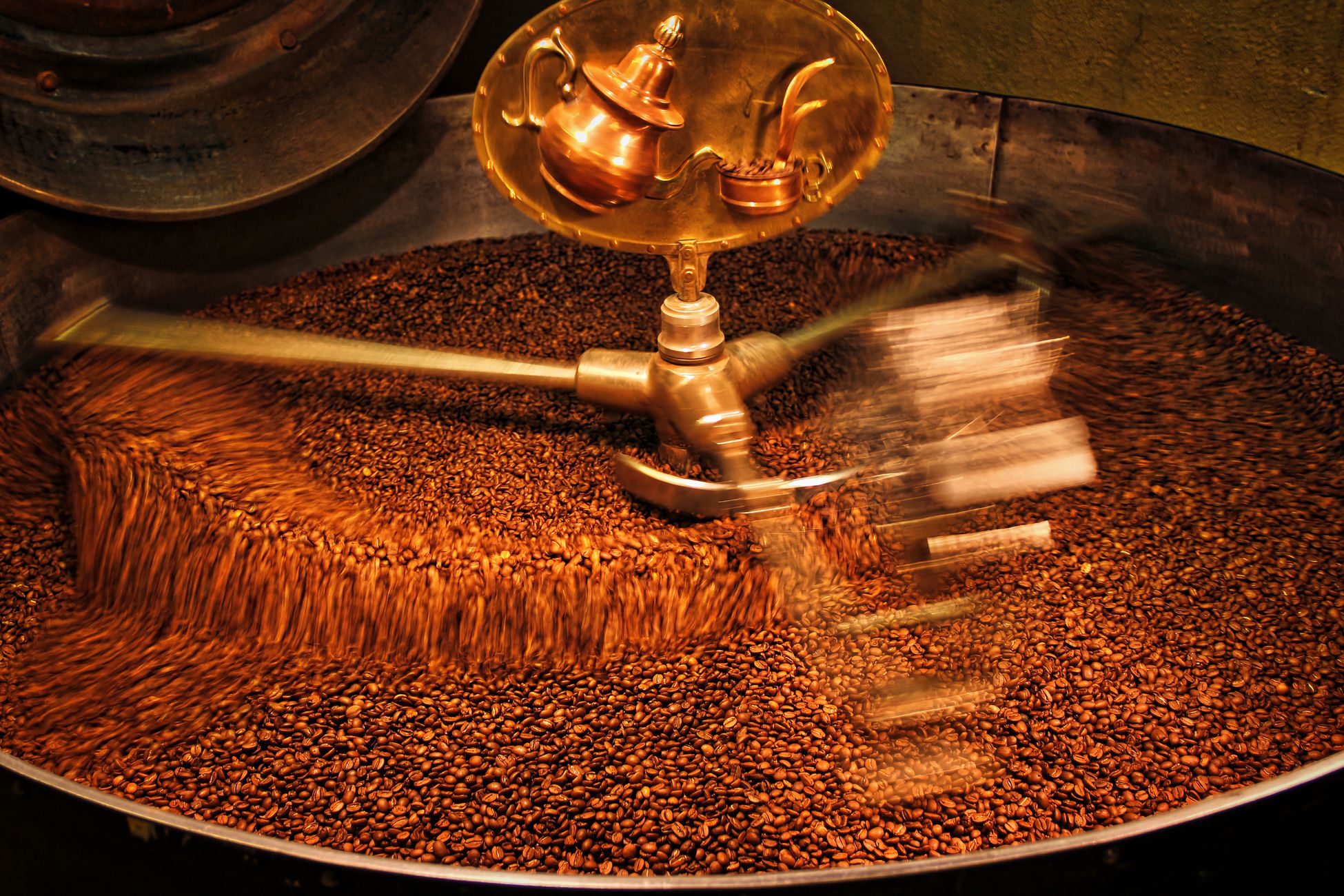 A close-up view of coffee beans being roasted in an industrial drum roaster.