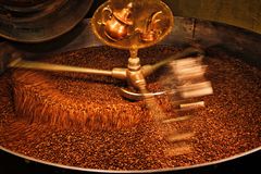 A close-up view of coffee beans being roasted in an industrial drum roaster.
