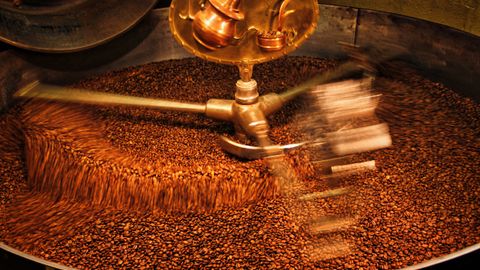 A close-up view of coffee beans being roasted in an industrial drum roaster.