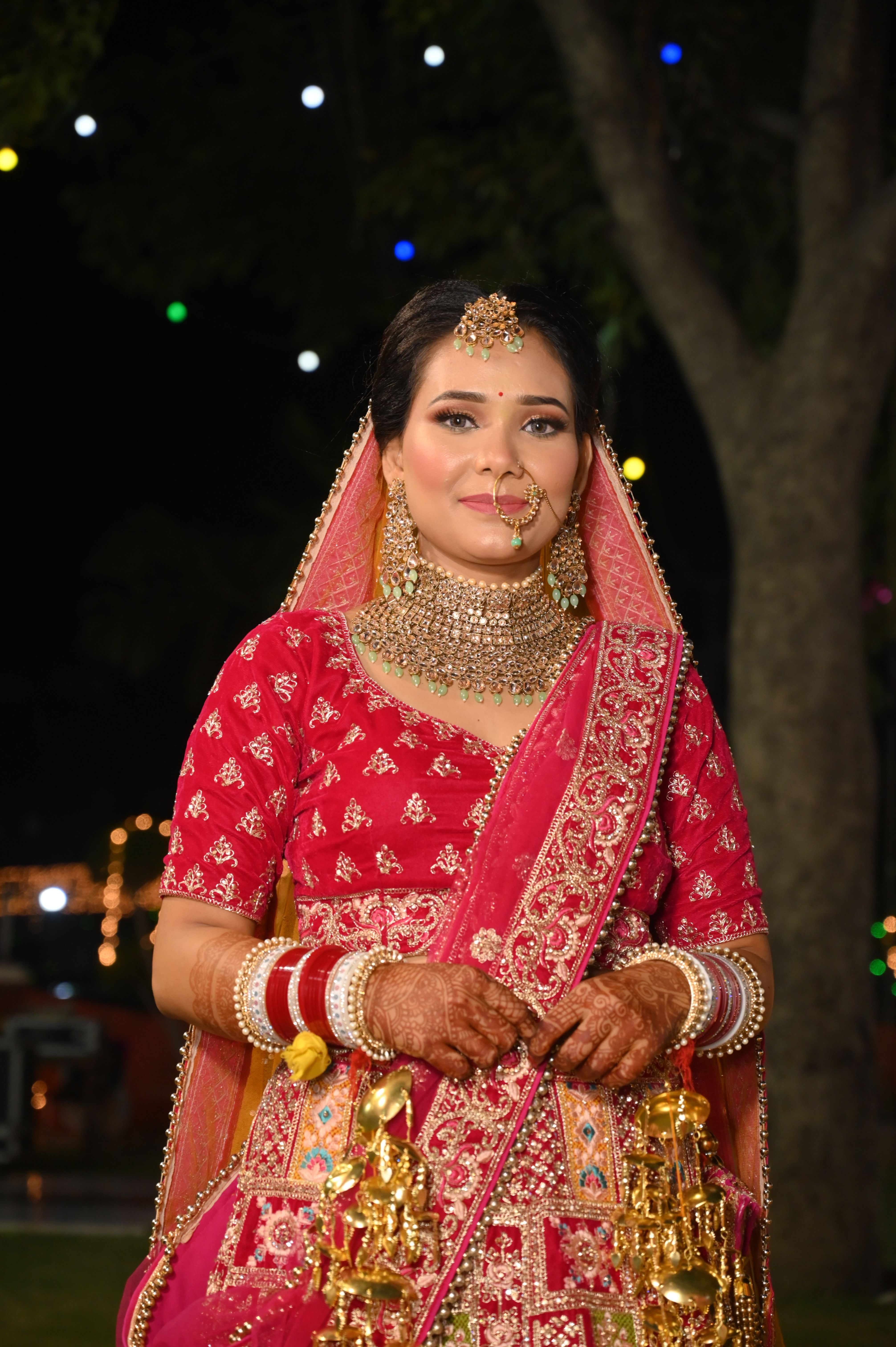 Portrait of an Indian bride in traditional red attire with intricate jewelry at night.
