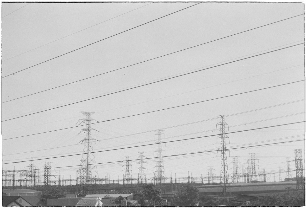 monochrome image of rows of power lines and pylons in an industrial zo