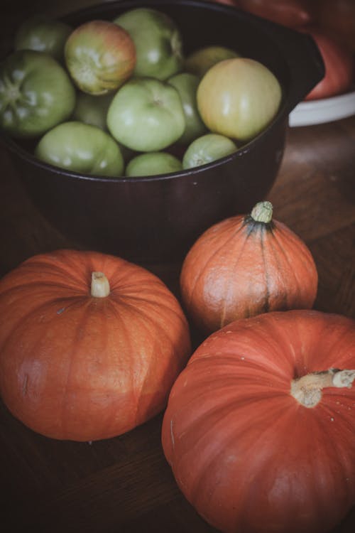 Pumpkins and a Bowl of Tomatoes Lying on a Table 