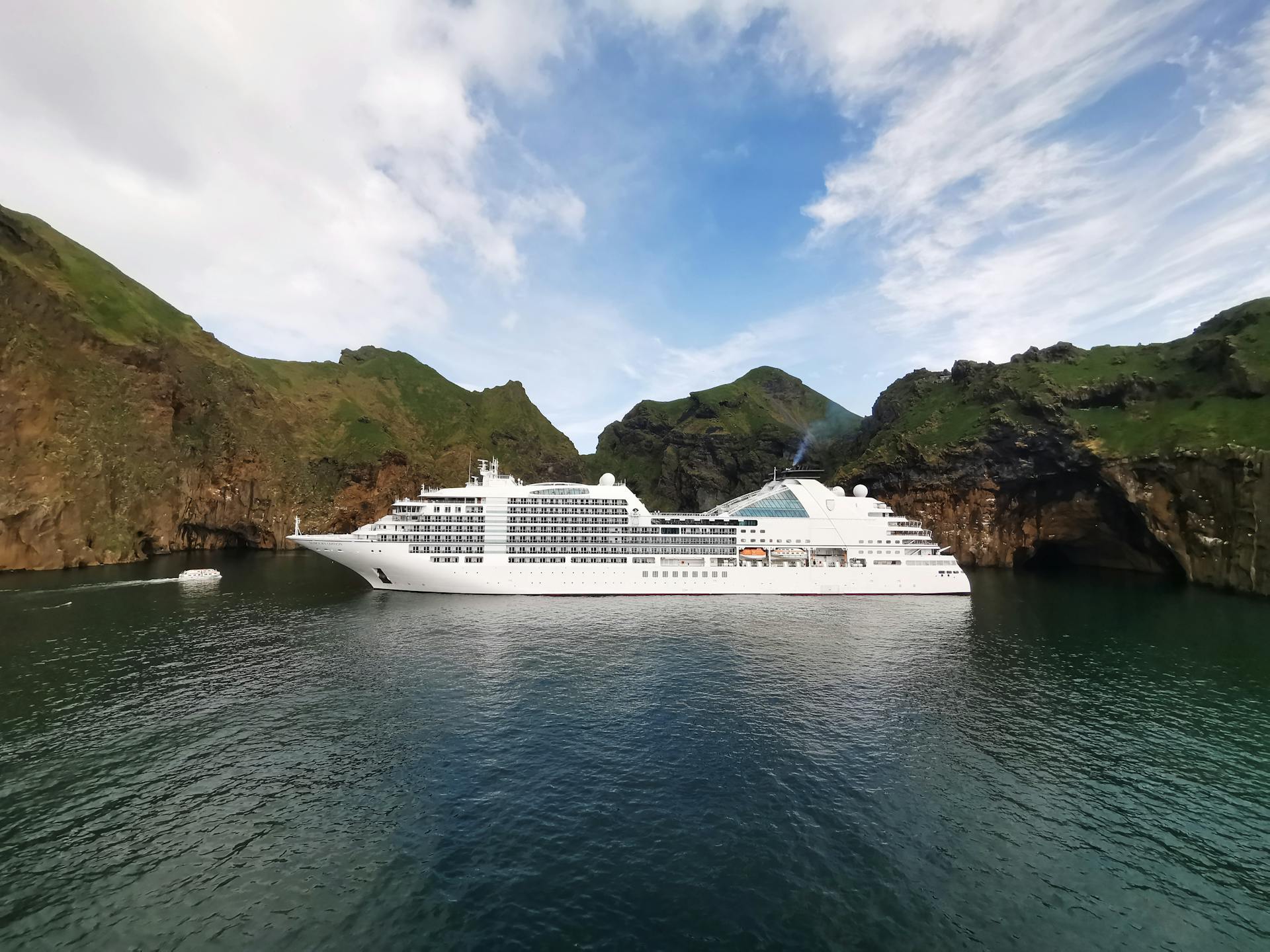 A stunning view of a luxury cruise ship in a picturesque Icelandic cove surrounded by cliffs.