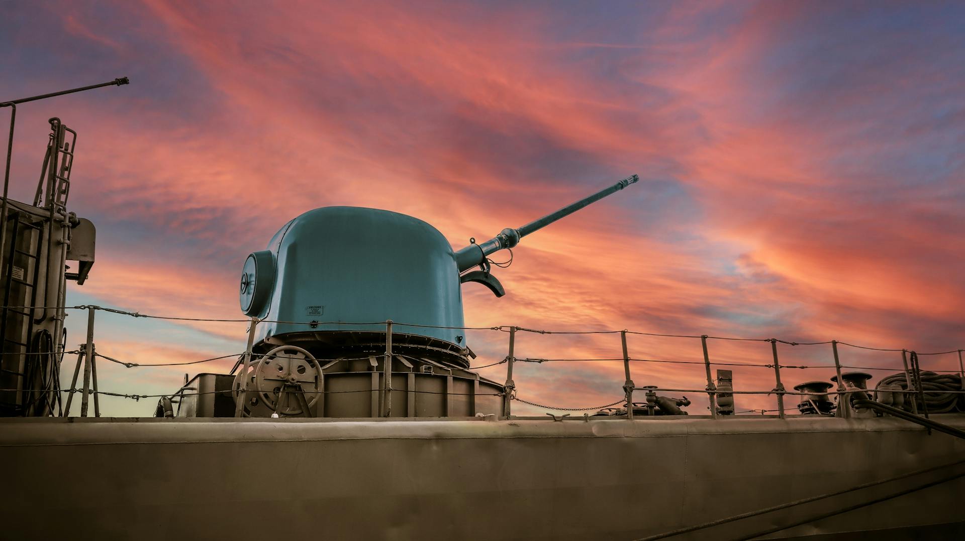 A military battleship showcased against a vibrant pink sunset in Málaga, España.