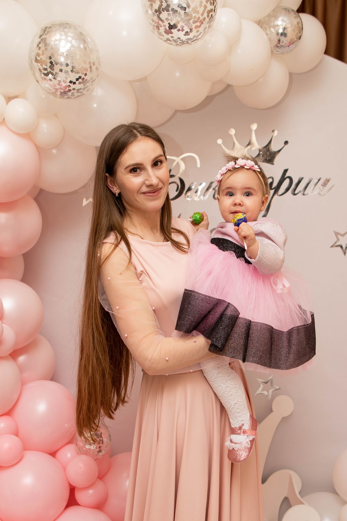 Mother holding baby with pink and white balloons