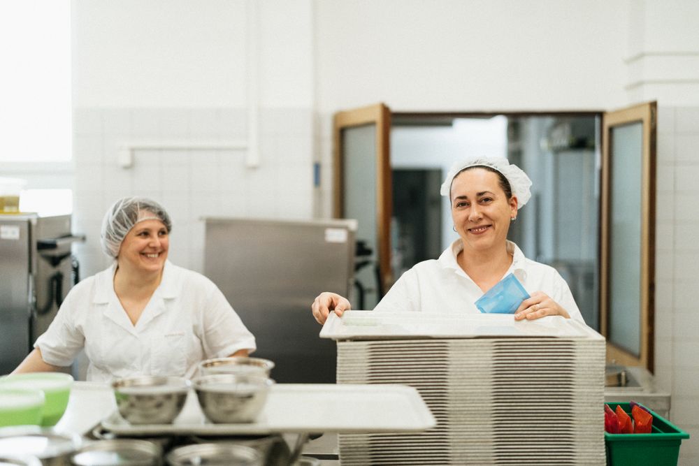 Equipe de cozinha uniformizada trabalhando no refeitório de uma empresa