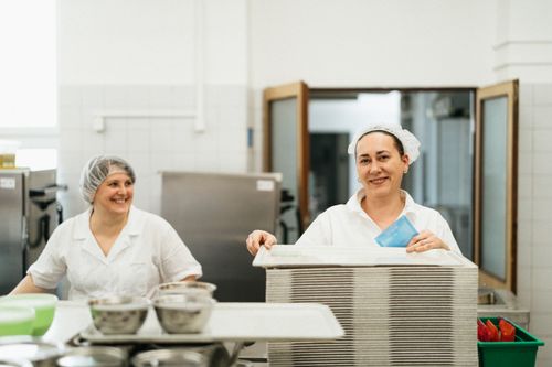 Free Friendly cafeteria staff working together in a kitchen, showcasing teamwork and service. Stock Photo