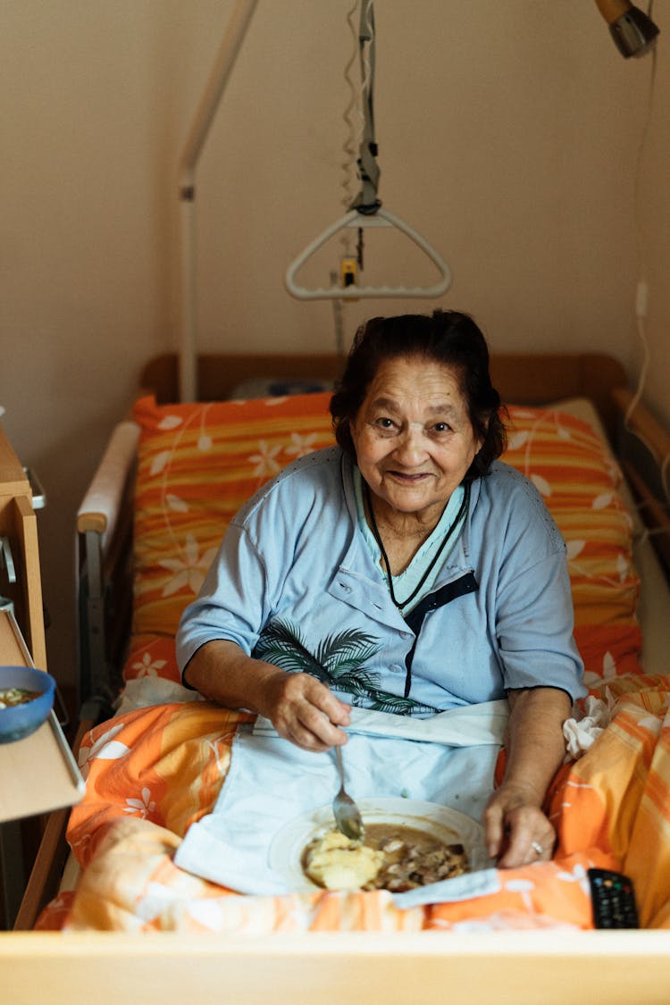 Senior Woman Sitting In Bed And Eating