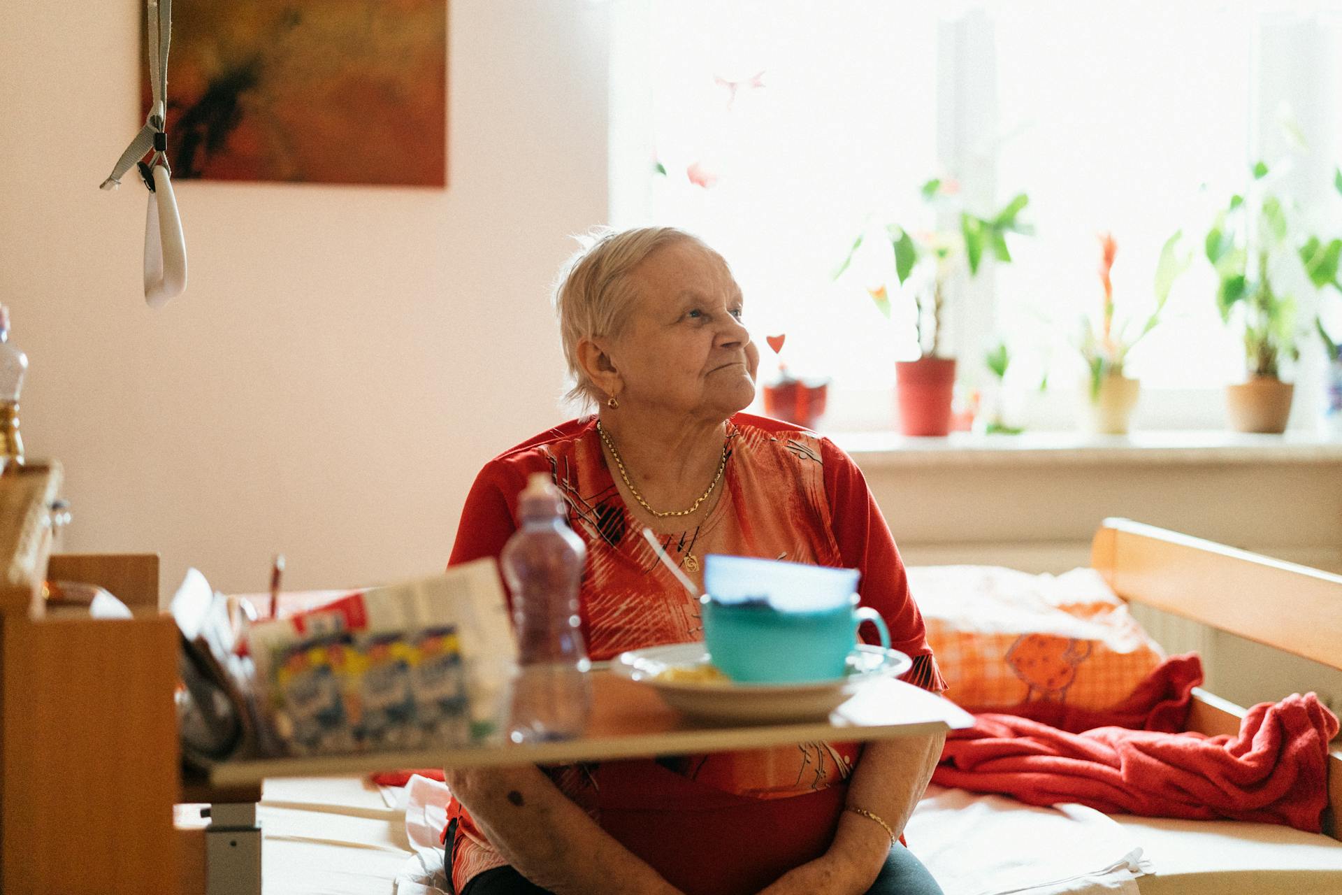 Senior woman in a retirement home sitting by a table with flowers, exuding warmth and comfort.