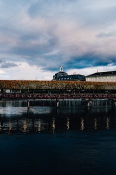 Chapel Bridge over calm river reflecting dramatic sky in Lucerne.