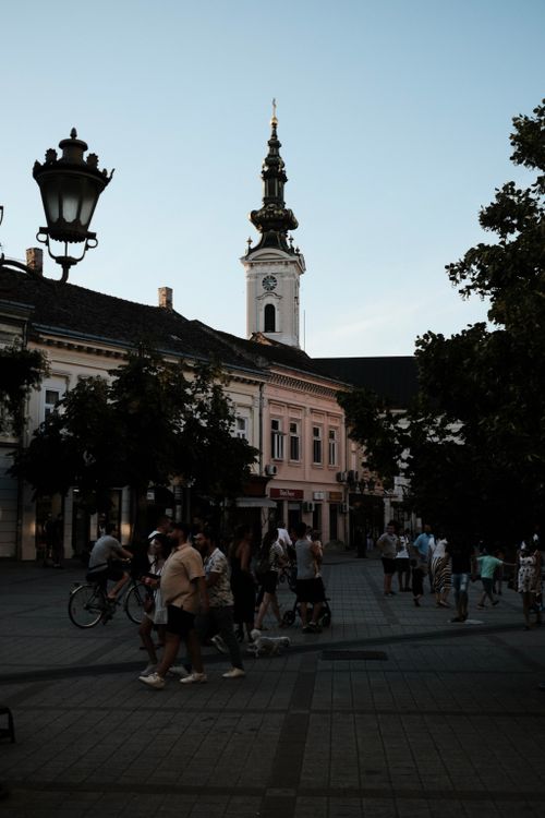 Free Bustling town square in Novi Sad with Saint George's Cathedral at dusk. Stock Photo