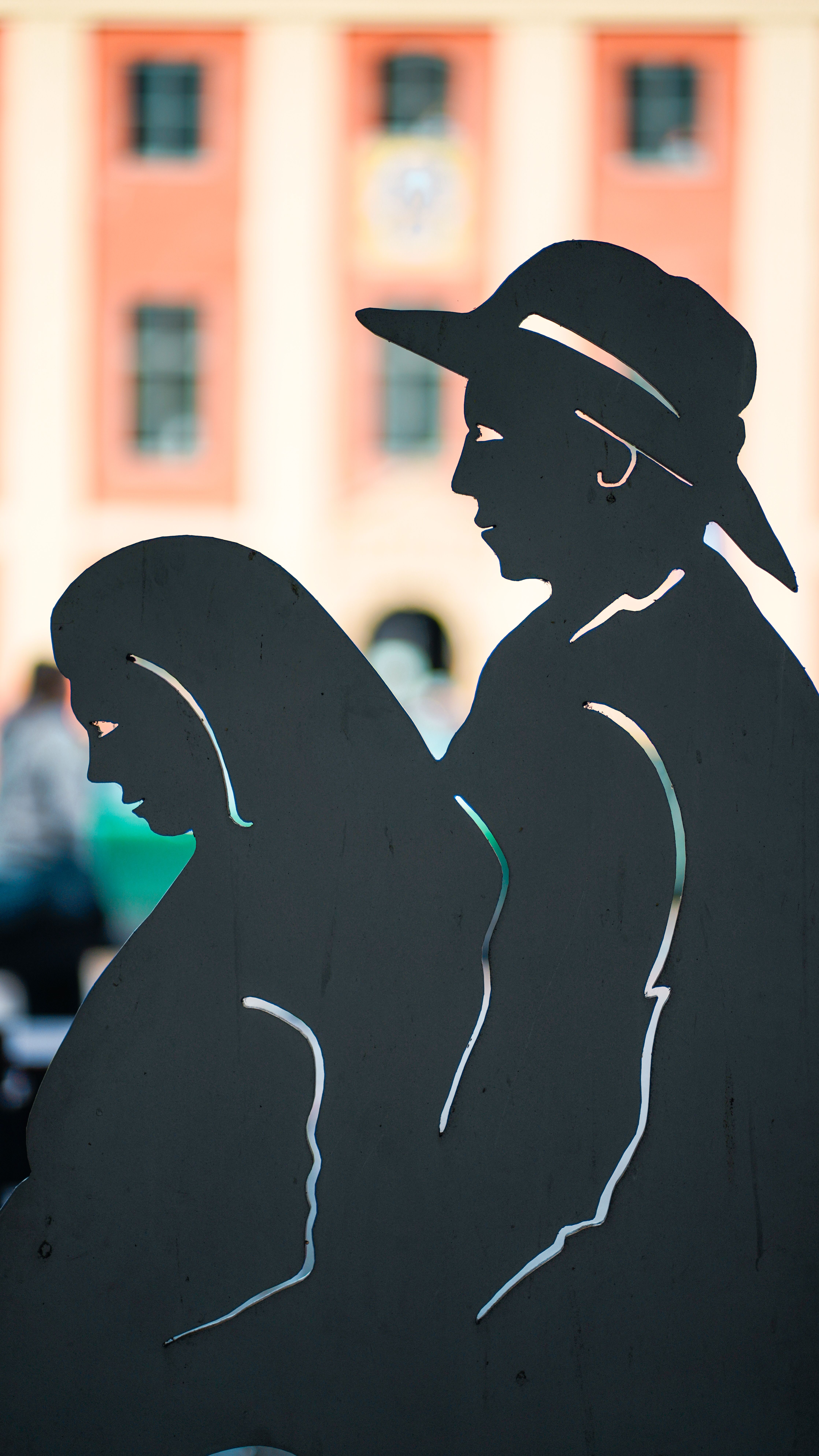 Fotomural Silsiueta de escultura de figuras frente a una fachada de edificio histórico.