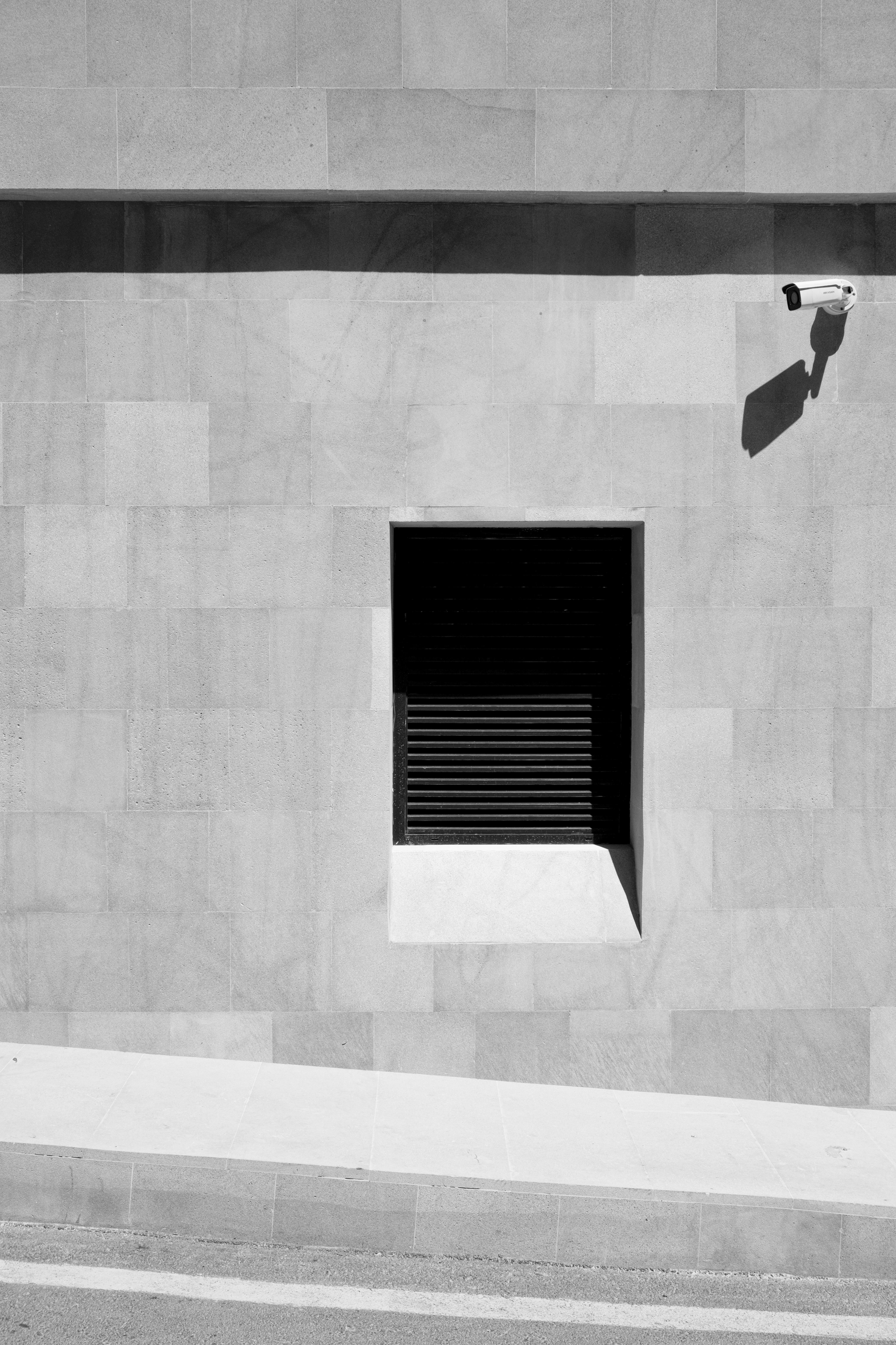 Contemporary building facade featuring a window and security camera, emphasizing urban security.