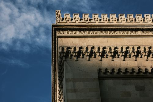 Free Close-up of an ornate architectural facade with intricate stonework against a clear blue sky. Stock Photo