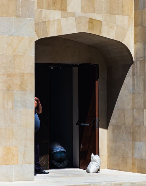 Free Person standing near a sunlit archway with an open door, casting shadows. Stock Photo