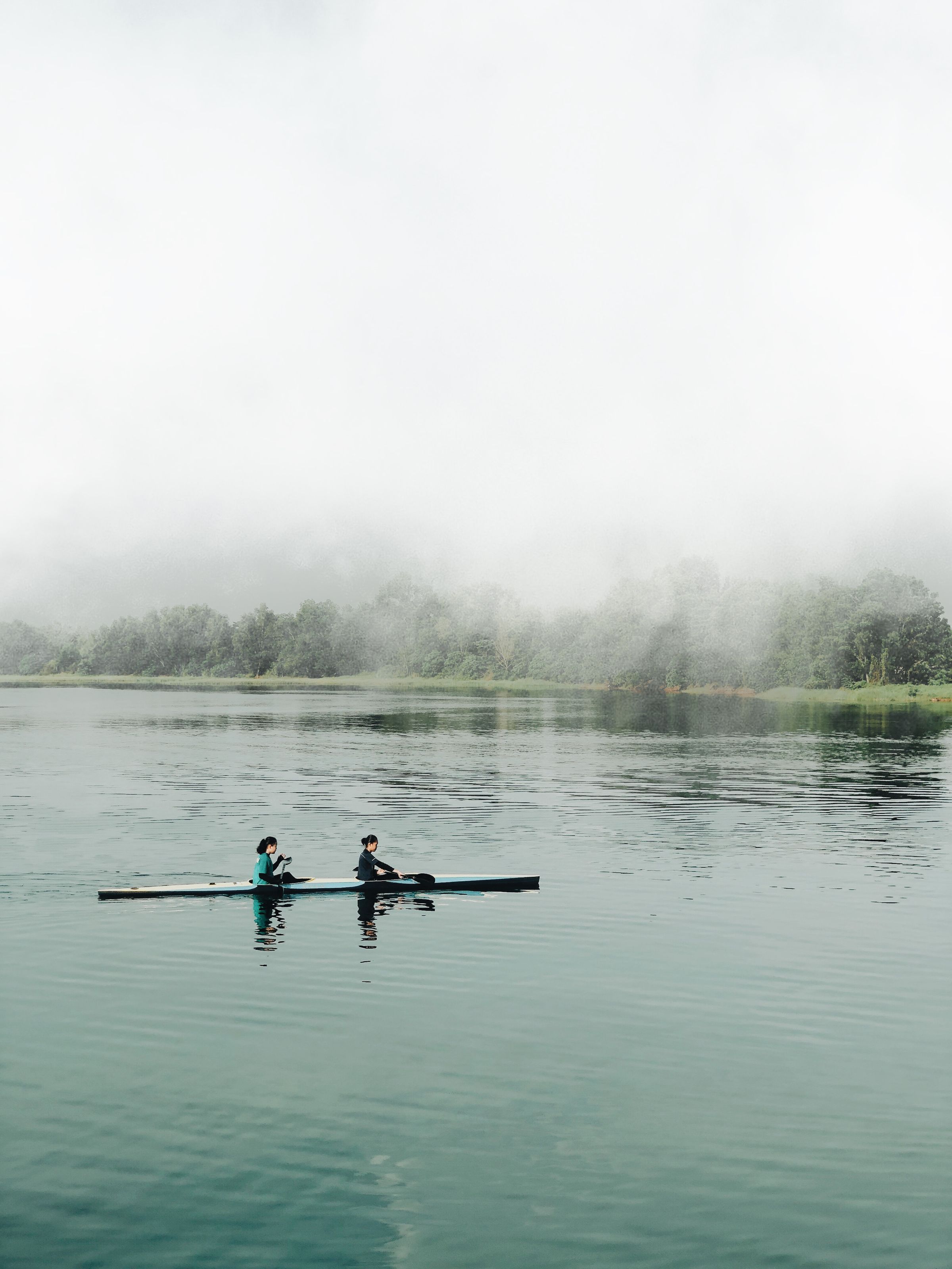 Kayakers moving across a quiet misty lake