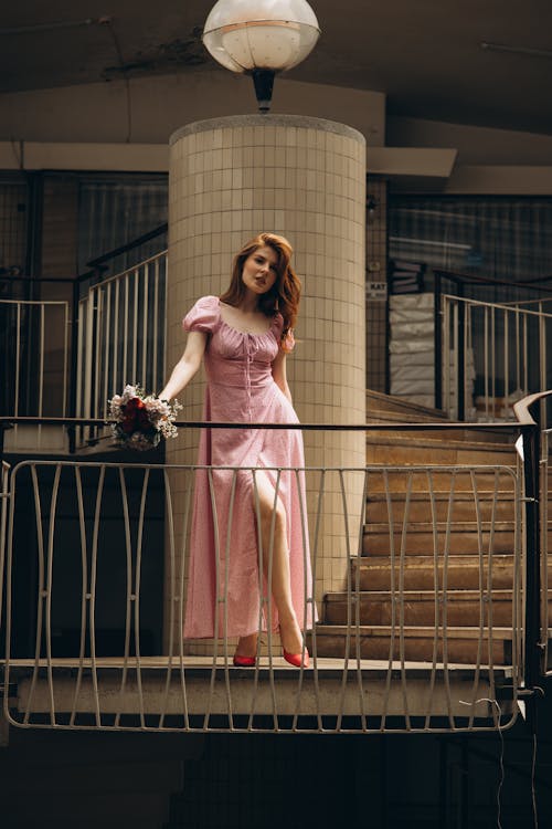 A woman in a pink dress standing on a balcony
