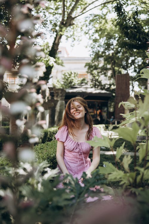 A woman in a pink dress is sitting in a garden