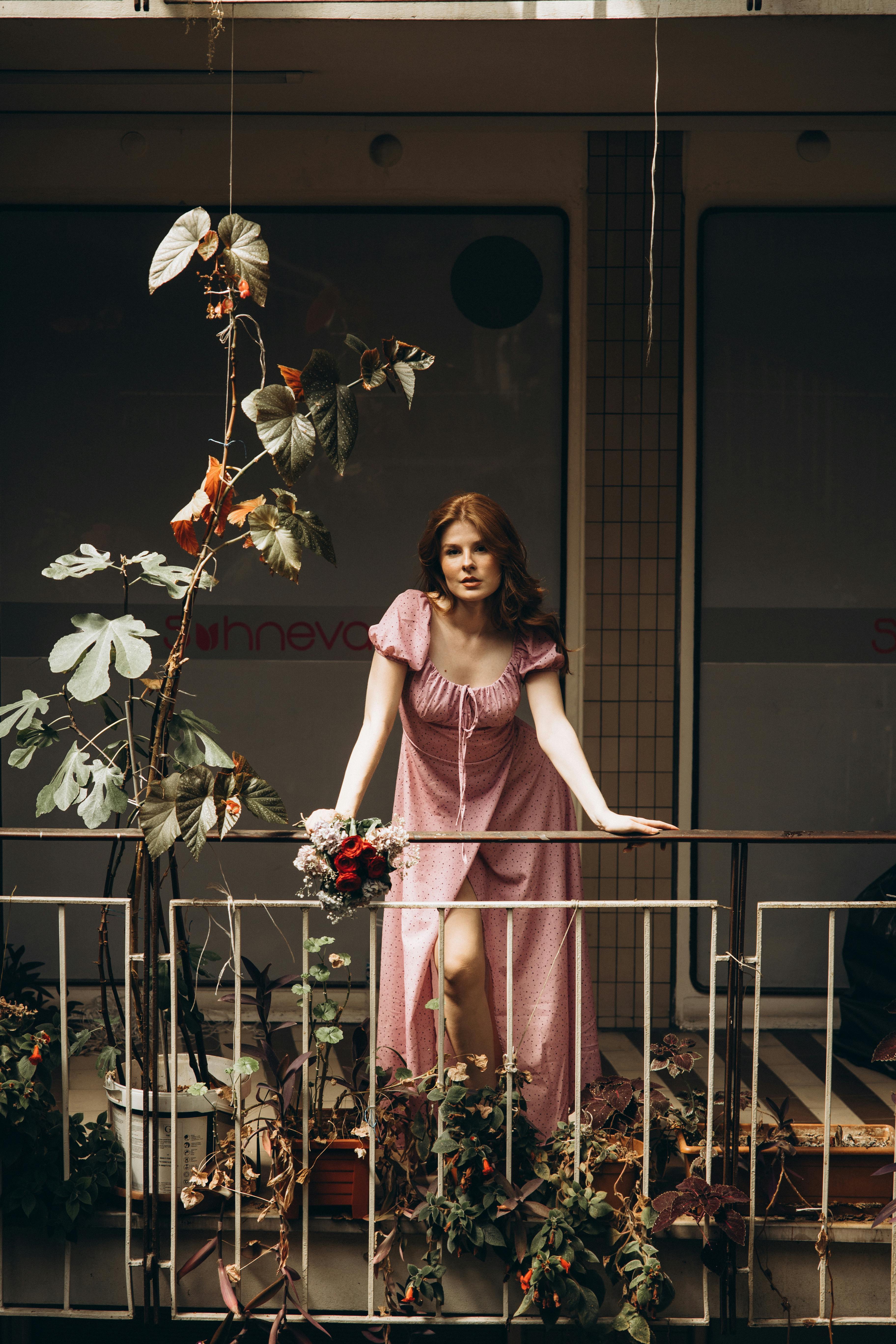 a woman in a pink dress standing on a balcony