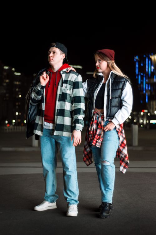 Free A stylish young couple in urban streetwear posing confidently on a city street at night. Stock Photo