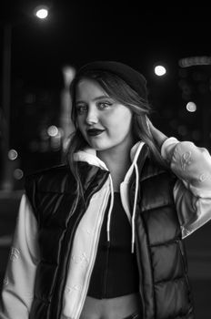 Portrait of a fashionable woman wearing a hat and vest in a city at night.