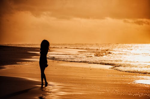 Silhouette of Woman on Beach at Golden Sunset