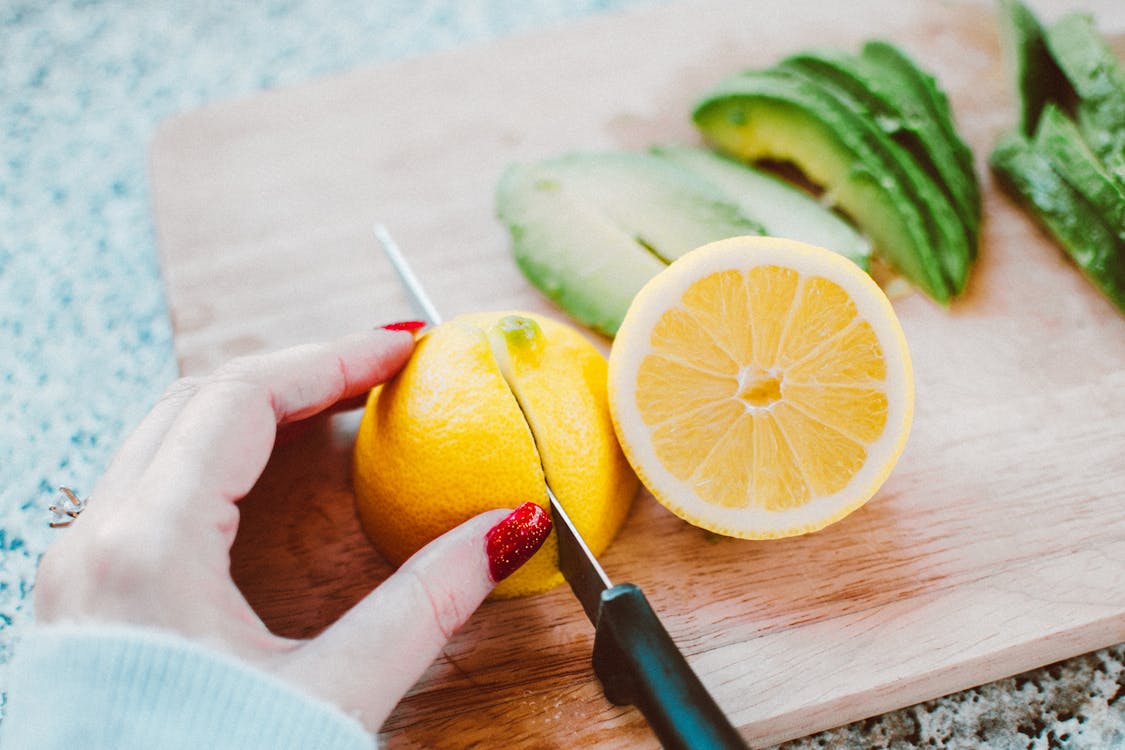 Free Person Slicing Lemon on Wooden Chopping Board Stock Photo
