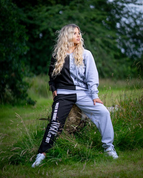 Blonde Woman in Sports Suit Sits on Rock