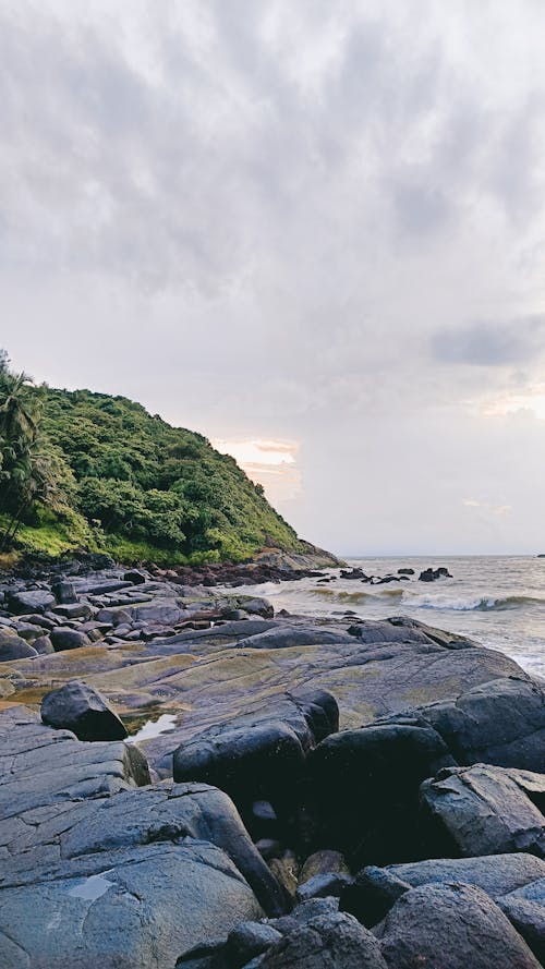 Foto stok gratis bebatuan tebing, gunung hijau, laut yang tenang