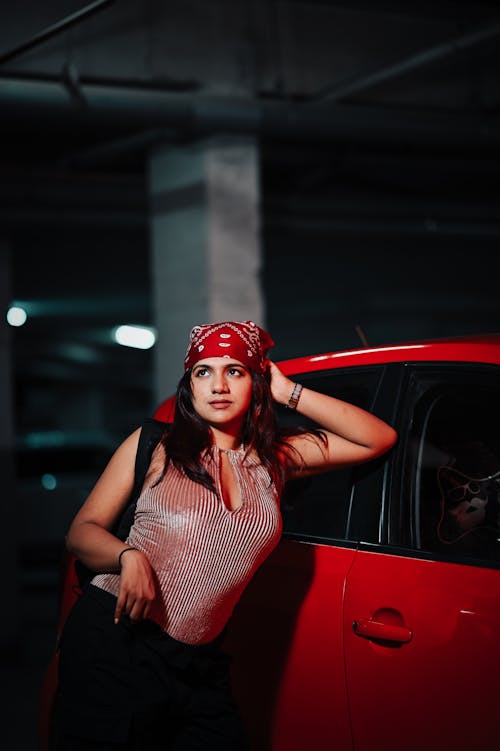 Young Woman Leaning against a Red Car 