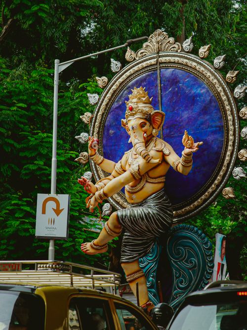Free A colorful Ganesha statue amidst the bustling streets of Mumbai, capturing the essence of Hindu culture and city life. Stock Photo
