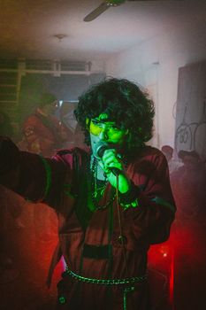 A dynamic indoor performance featuring a singer with colorful lighting and a lively atmosphere.