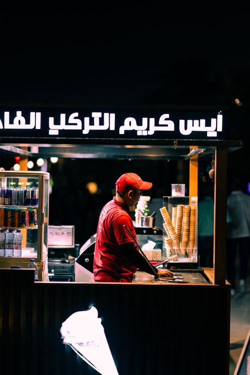 Free Ice cream vendor at night in a bustling urban environment, serving from a booth. Stock Photo