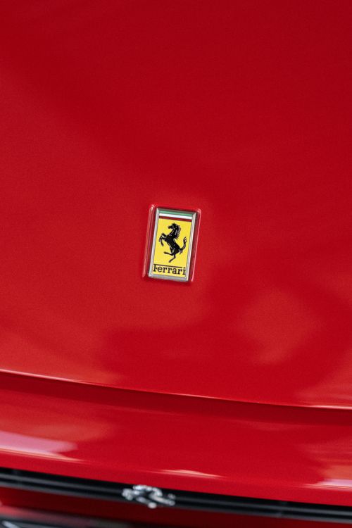 Free Detailed close-up of a red Ferrari hood featuring the iconic logo. Stock Photo