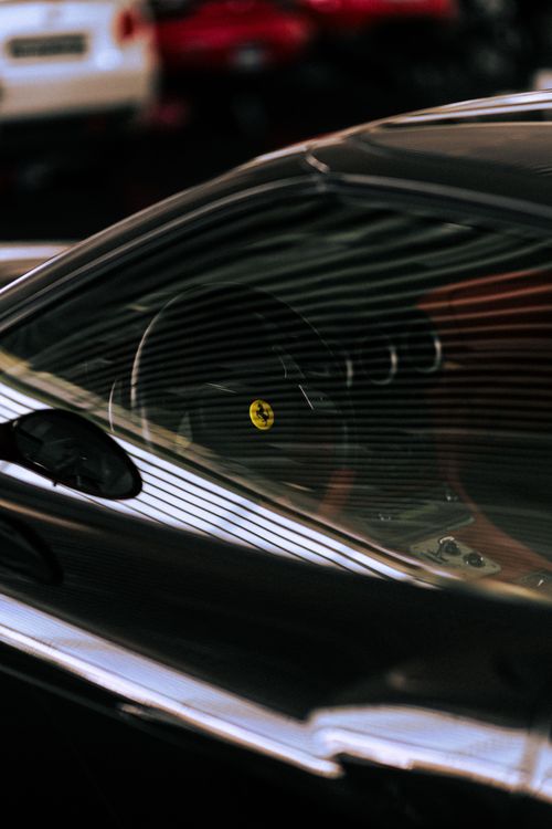 Free Close-up of a luxury sports car interior focusing on the sleek design and emblematic steering wheel. Stock Photo
