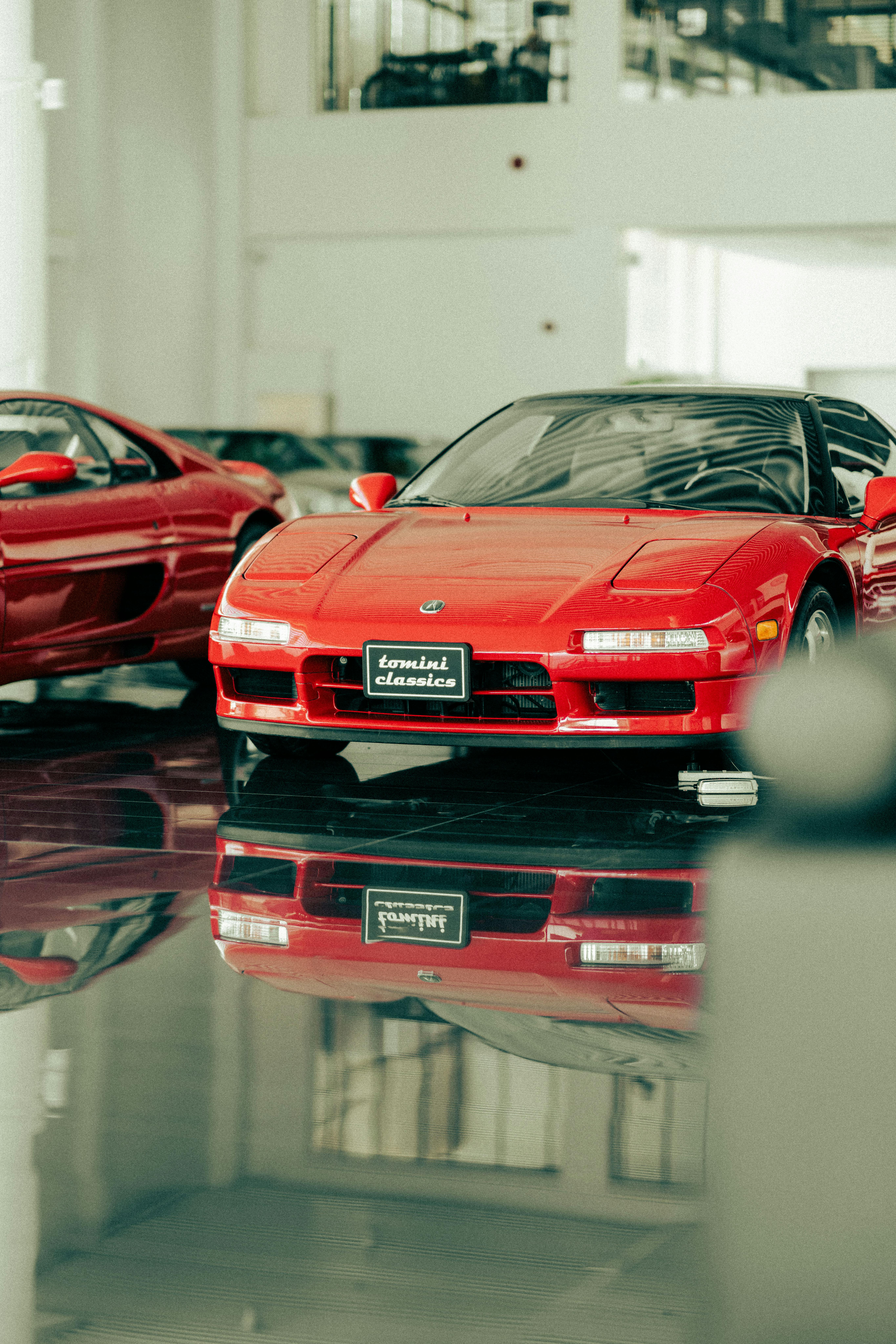 Elegant red sports car displayed in a luxury car showroom, reflecting a blend of classic and modern automotive design.