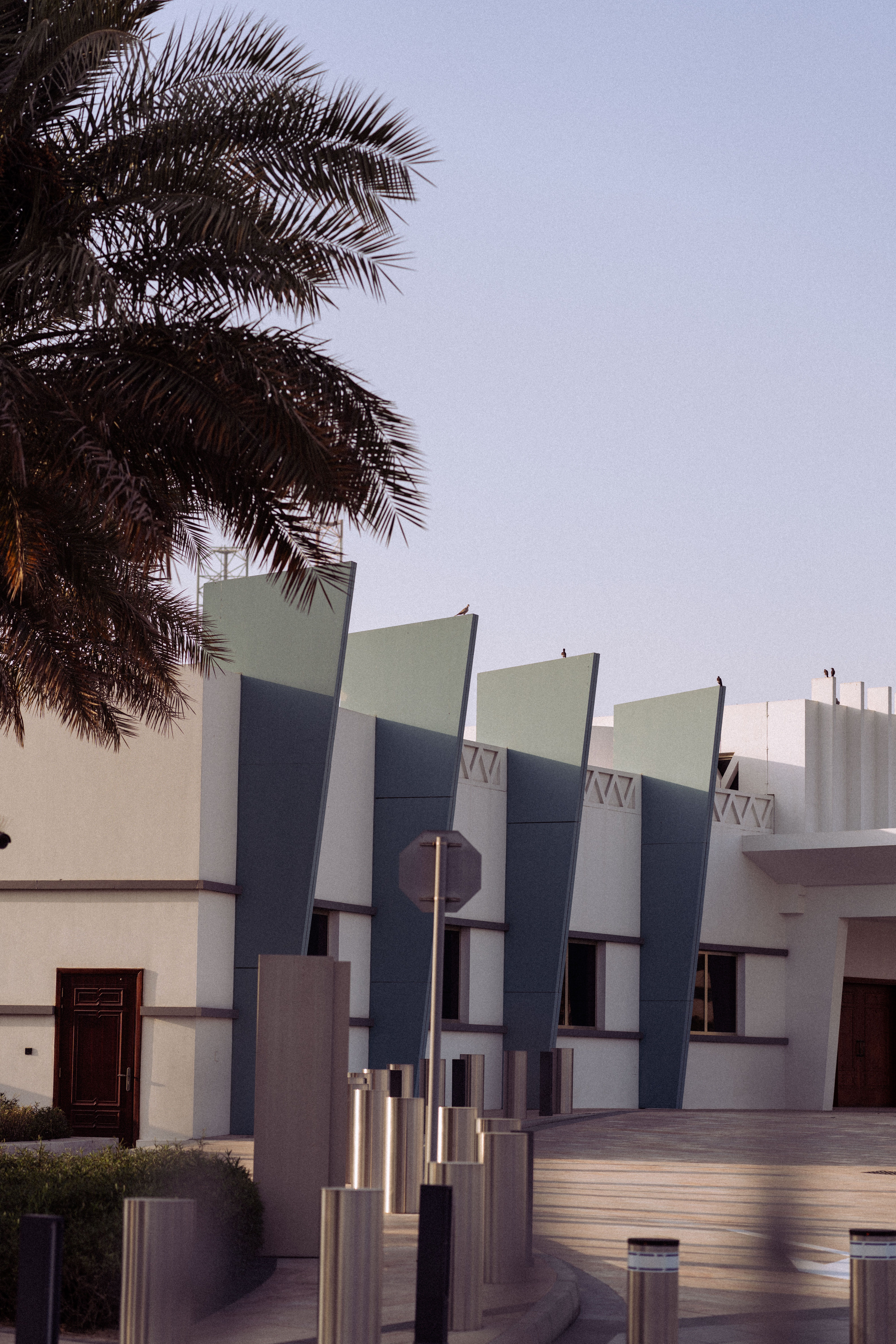 Exterior view of Etihad Museum in Dubai showcasing modern architecture and palm tree under a clear sky.