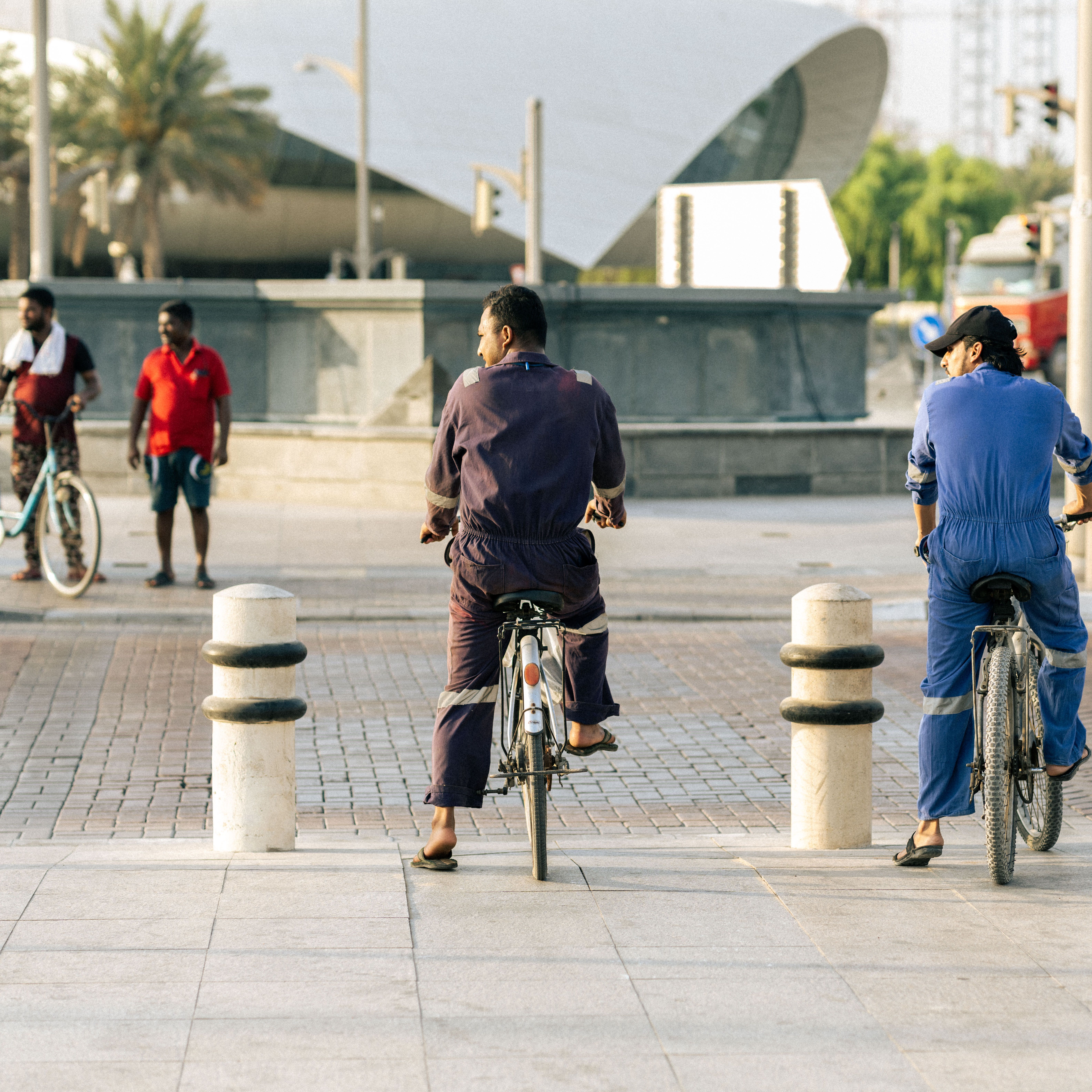 A group of cyclists and pedestrians sharing city streets with modern architecture in the background.