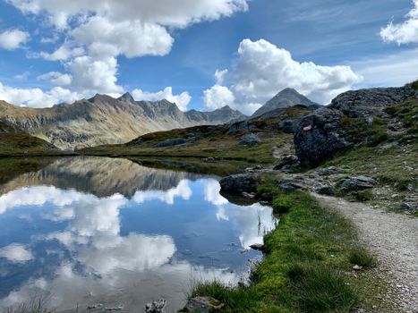 Panorama with Fluffy Clouds Reflecting in a Mountain Lake