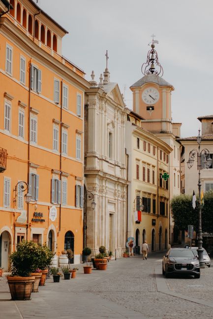 A picturesque street in Italy featuring historic buildings and a clock tower, perfect for travel imagery.