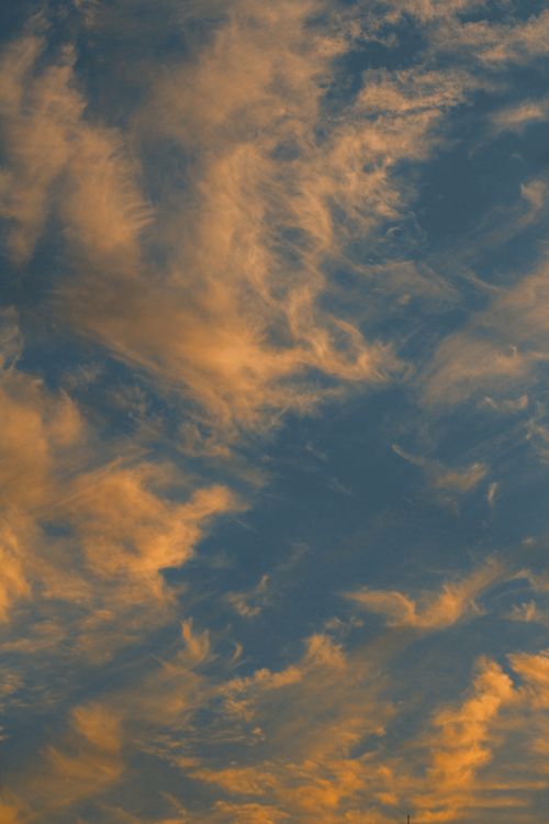 Free Dramatic golden clouds during sunset create a vibrant evening sky scene. Stock Photo