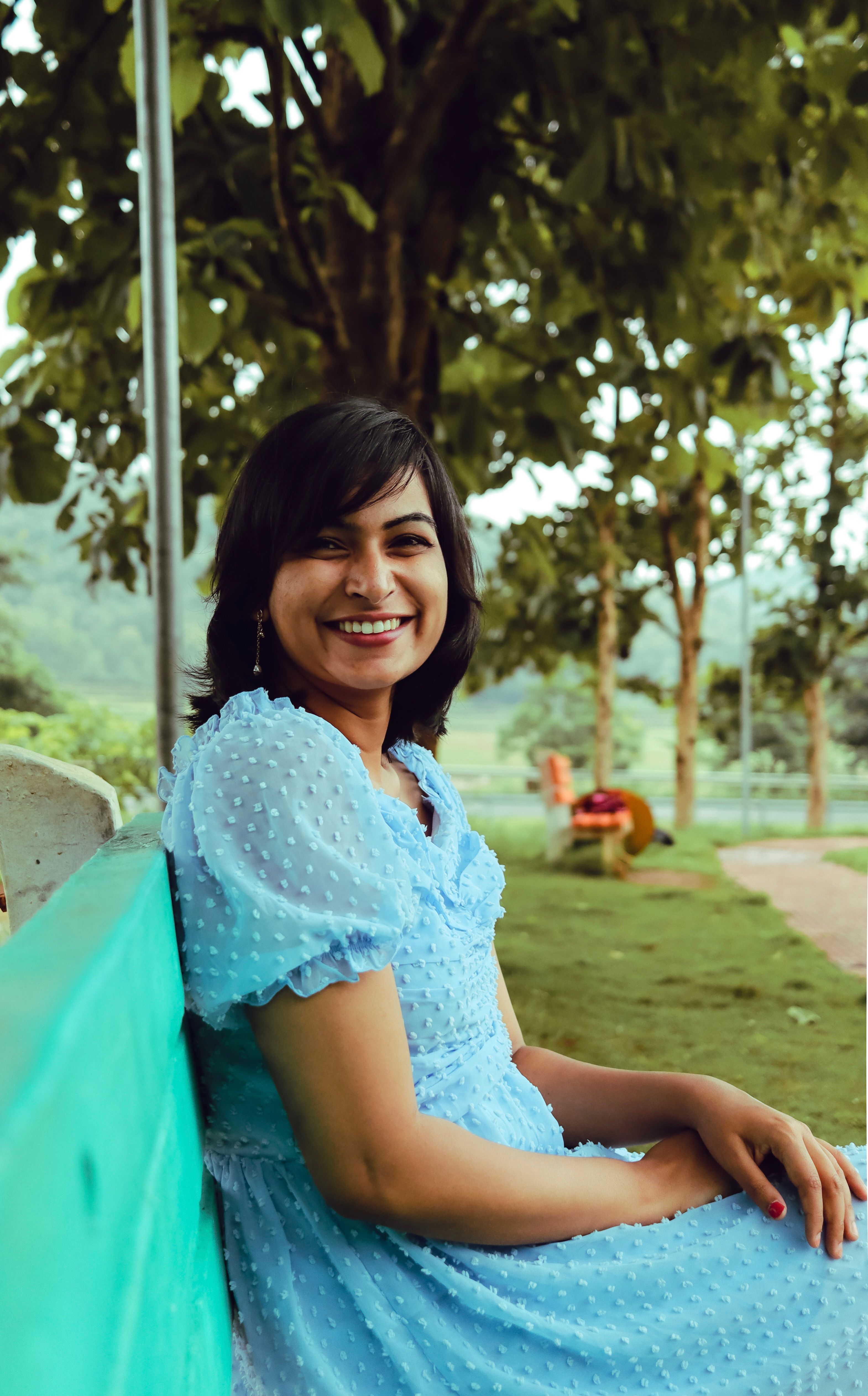 Smiling Woman in Blue Dress Sitting on Bench in Park · Free Stock Photo