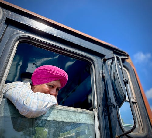 Man in Pink Turban Resting against Open Window of Truck Cabin